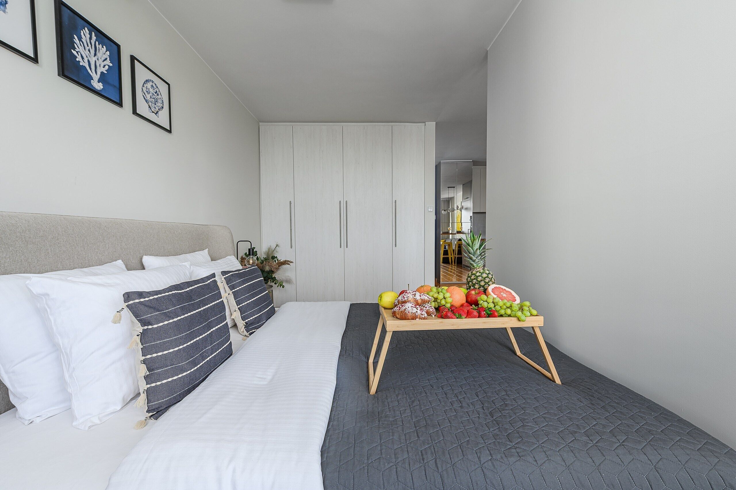 Ein Schlafzimmer mit einem Bett, Kissen, einem Nachttisch mit Obst und einem Kleiderschrank.