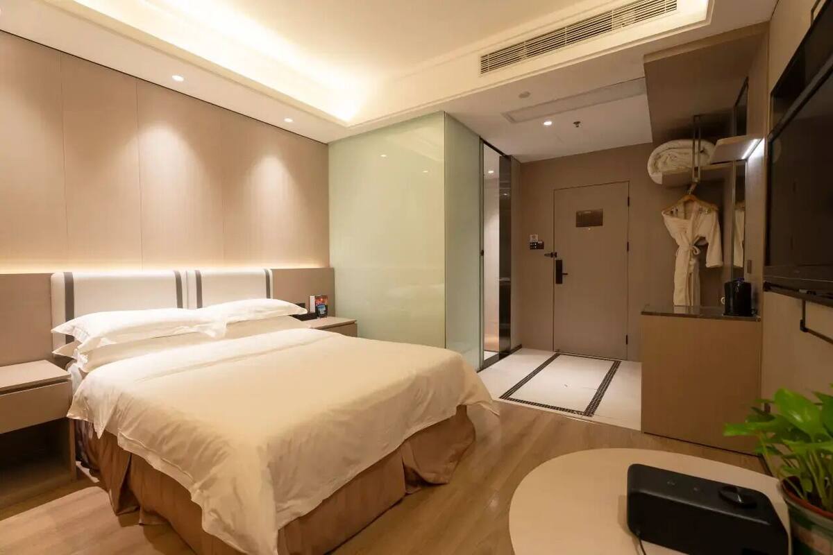 Una habitación de hotel moderna con una cama grande, mesitas de noche, un televisor de pantalla plana y un pequeño rincón de estar.