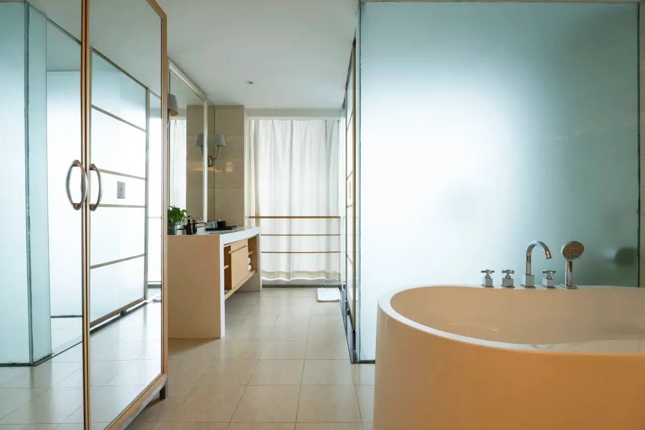 Un baño moderno con una bañera grande, cabina de ducha con paredes de vidrio y tocador con espejo.