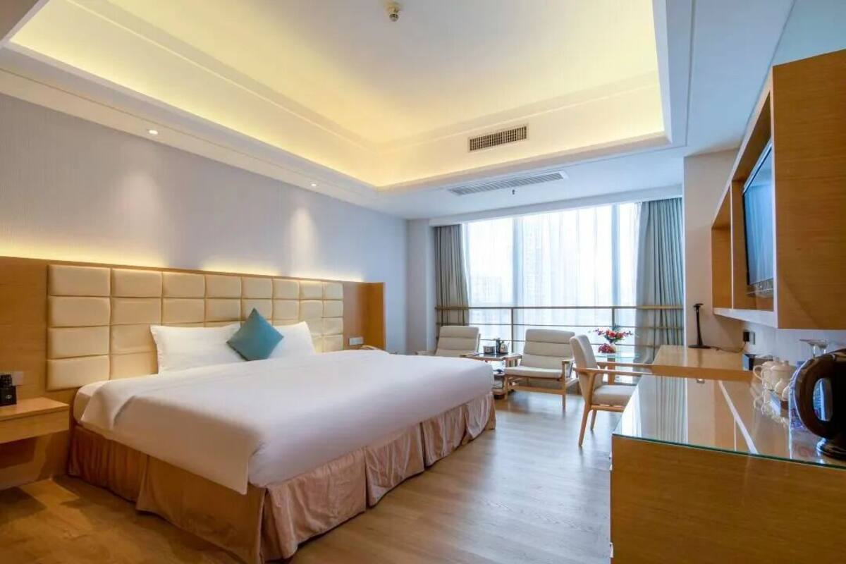 Una habitación de hotel con una cama grande, un escritorio, una silla y un televisor.