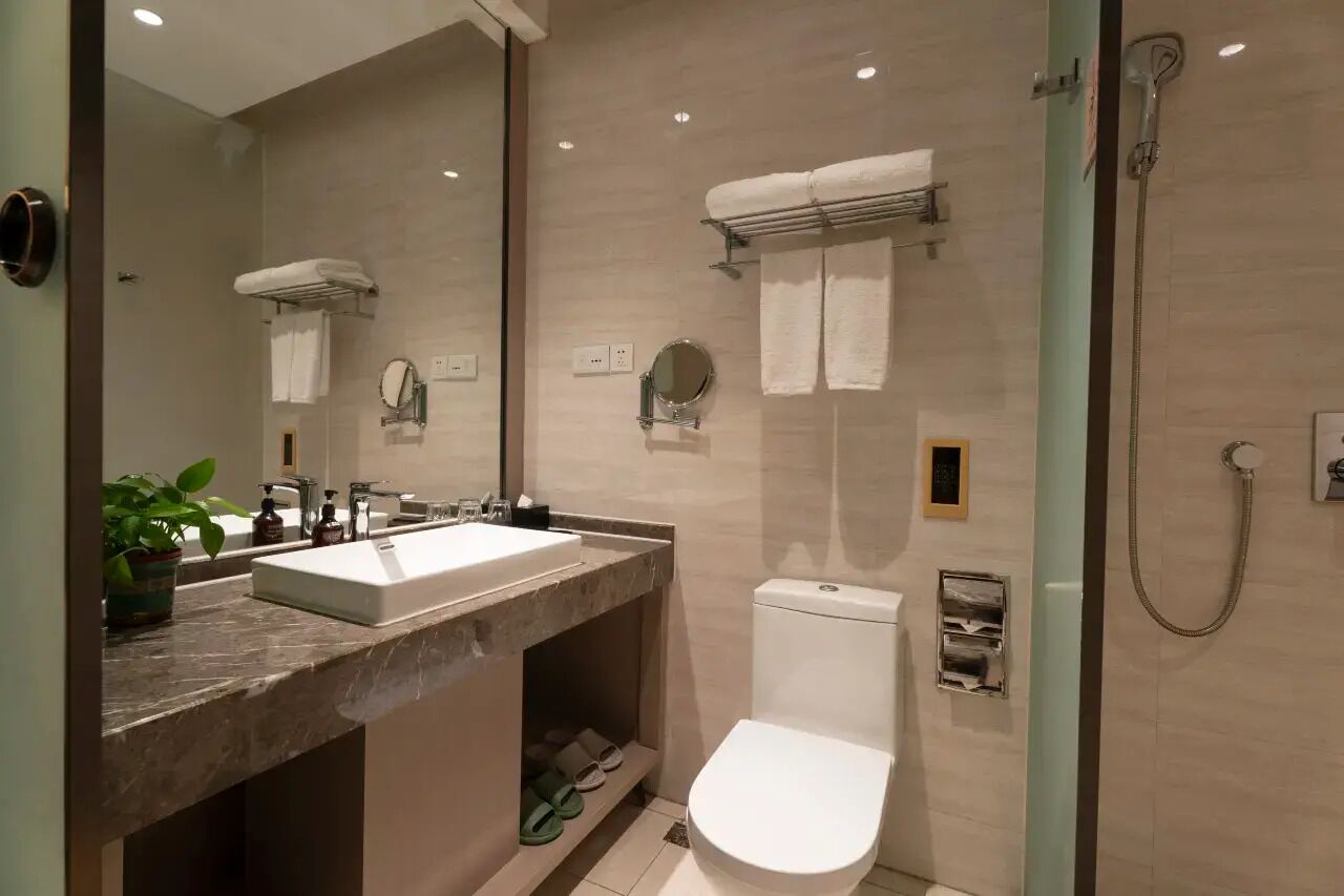 Ein modernes Badezimmer mit Marmorwaschtisch, Toilette, einer Duschkabine und einem Spiegel.