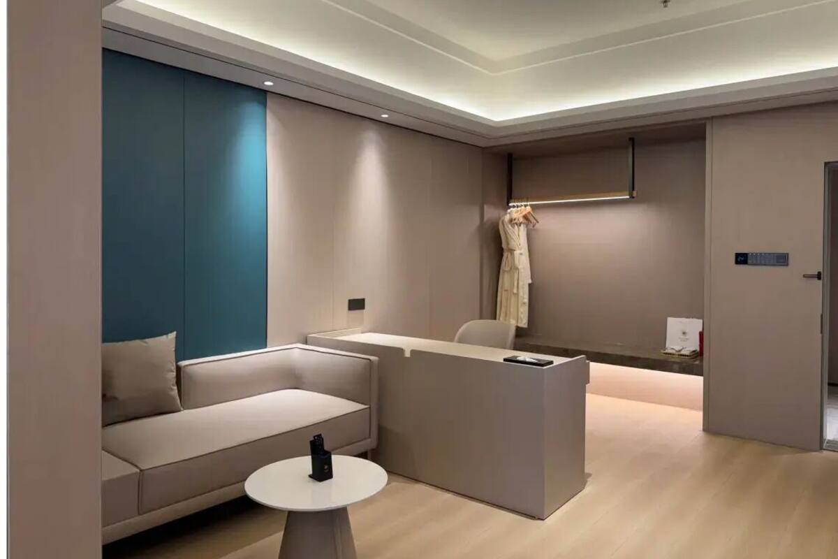 Una habitación de hotel moderna con un sofá, una mesita, un mostrador de recepción y una puerta.