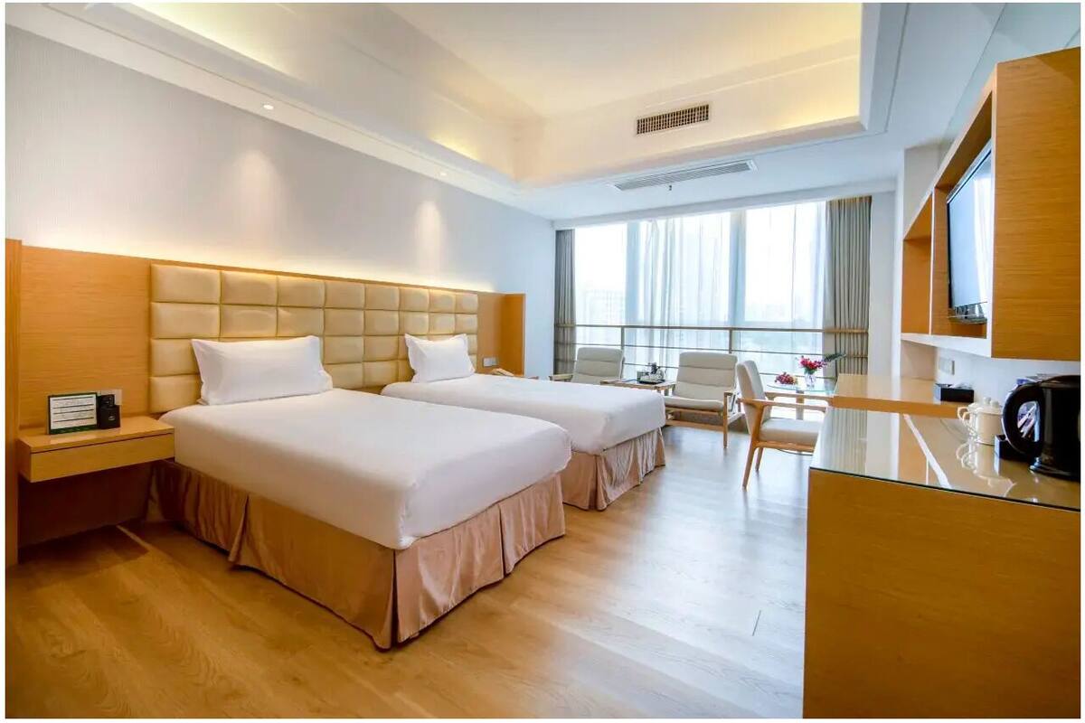 Habitación de hotel con dos camas, un escritorio, una silla y un televisor.