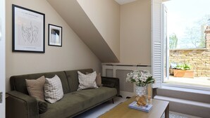 A living room with a green sofa, a wooden coffee table, and two framed artworks on the wall. - The Eaves on Santos Road (London)