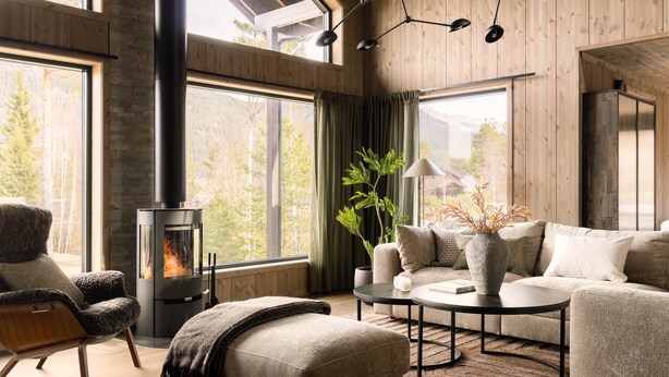 Un salon moderne avec une cheminée en pierre, des murs en bois et de grandes fenêtres.