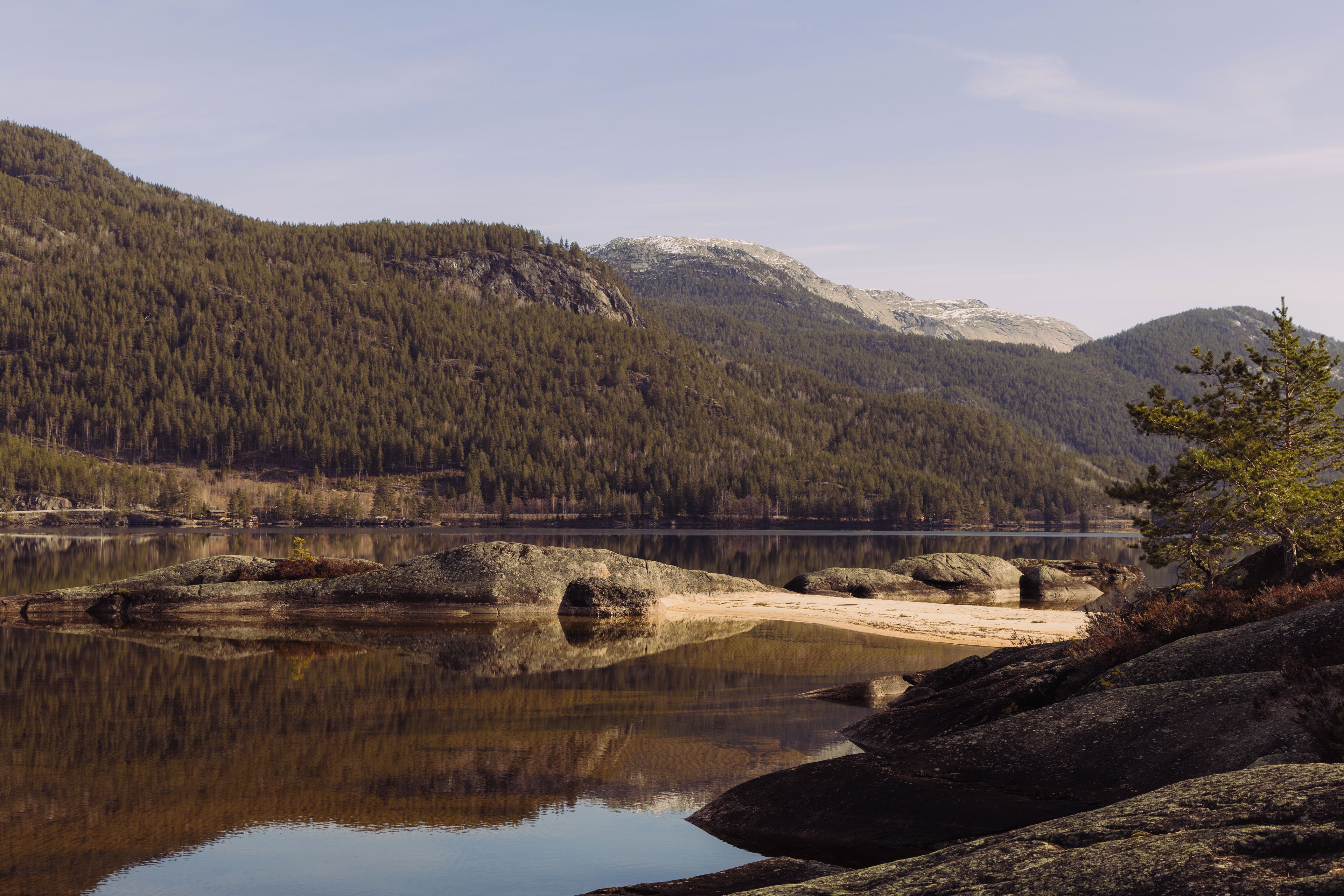 A tranquil lake surrounded by forested mountains and rocky shores.