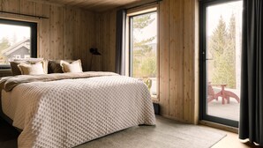 Un intérieur en bois avec un lit, de grandes fenêtres et une vue sur l’extérieur.