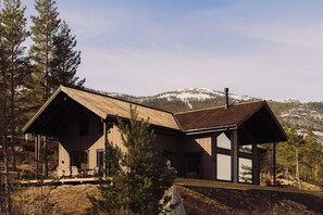 A cabin with a wooden exterior, large windows, and a covered porch. - Villa Fossen with sauna and jacuzzi (Vrådal)