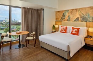 Una habitación de hotel con una cama grande, una mesa de comedor, dos sillas, vistas de la ciudad y un mural en la pared.