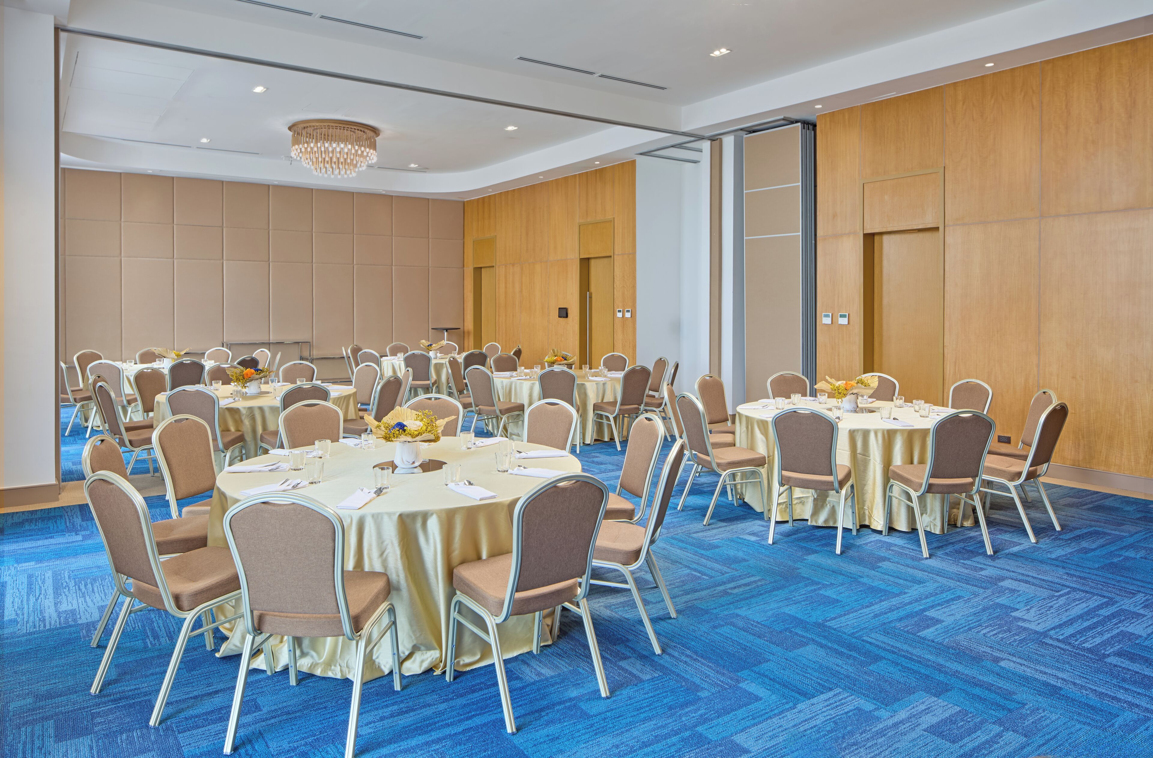 A conference room with round tables, chairs, and a chandelier.