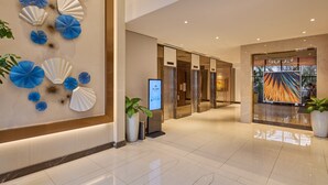A hotel lobby with a modern design, featuring a reception desk, a digital information kiosk, and a view of the hotel's interior. - Alino Hotel (Quezon City)