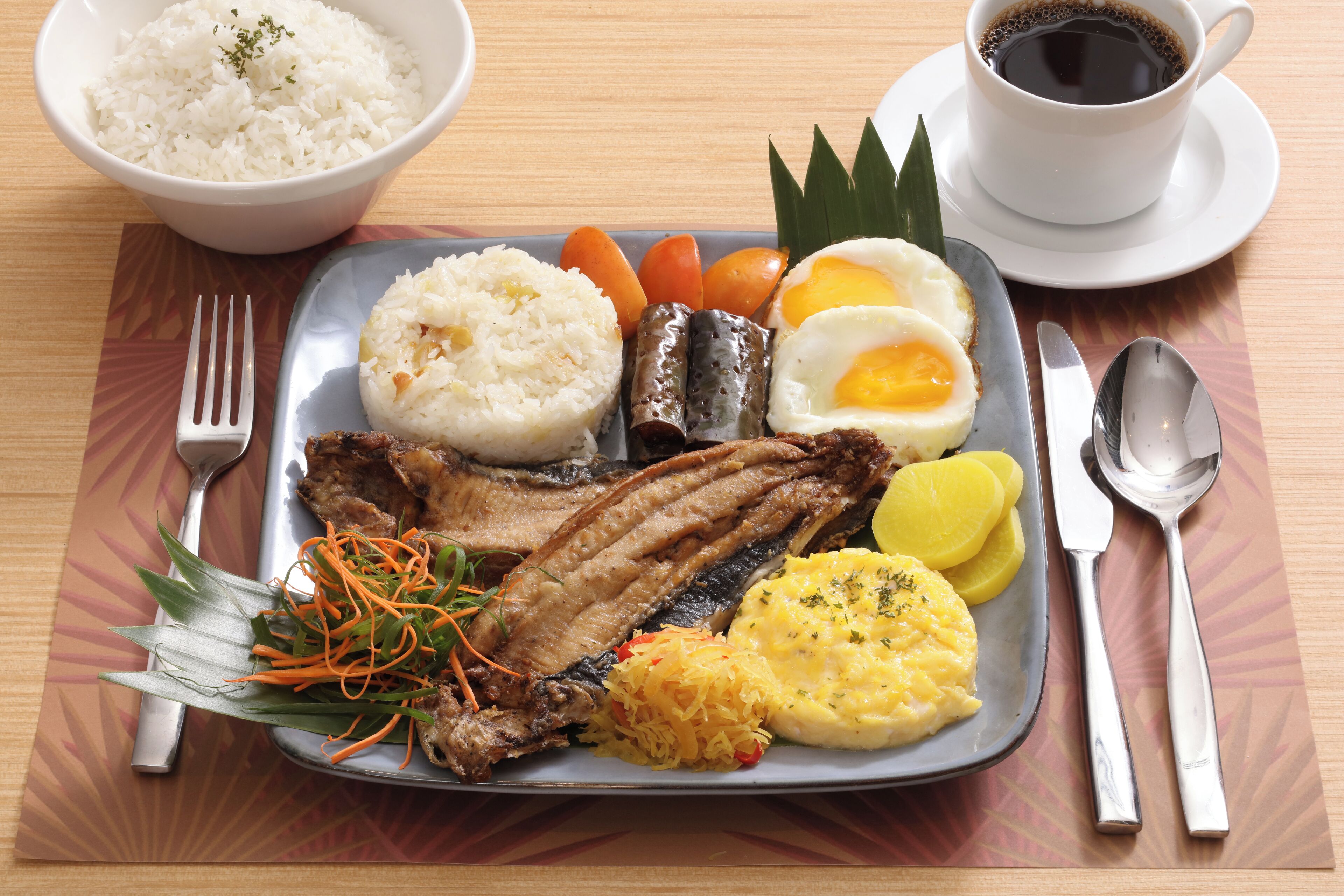Un plato de comida con arroz, pescado, huevos y verduras.