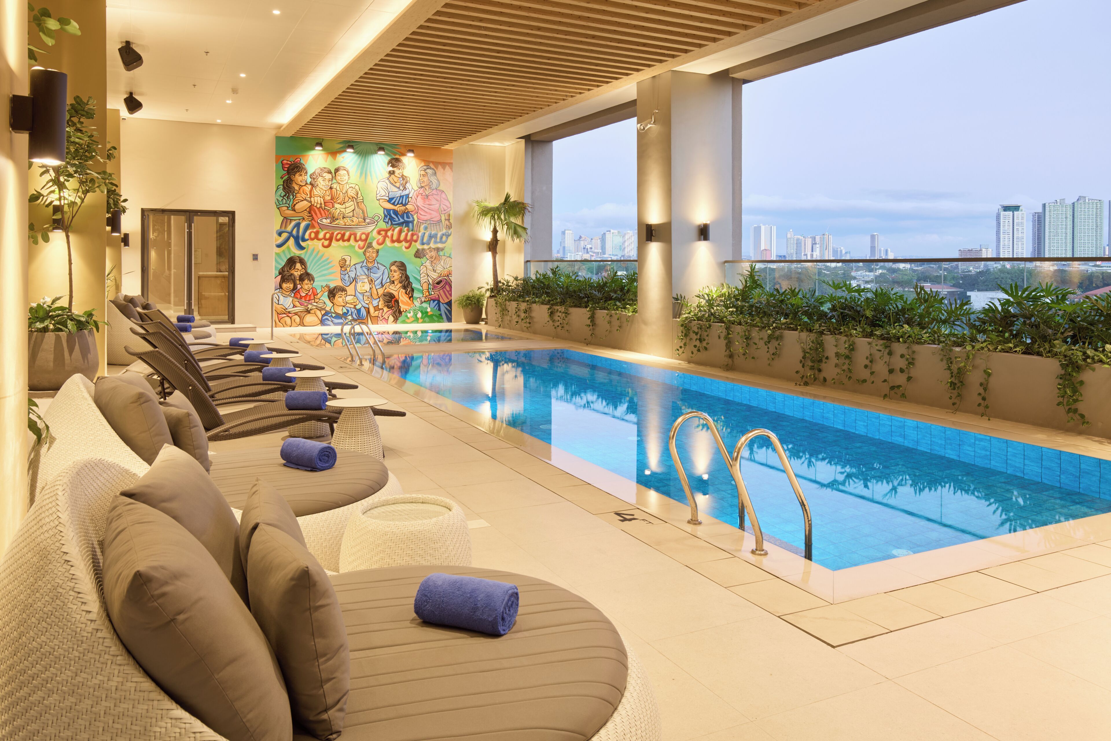 A modern indoor pool area with lounge chairs and a mural on the wall.
