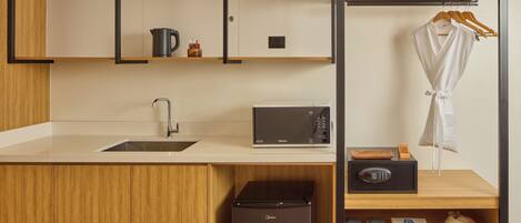 A compact kitchenette with a sink, microwave, and a small refrigerator.