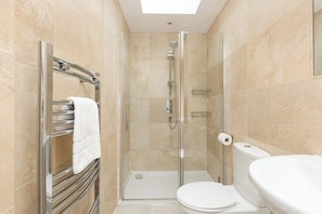 A modern bathroom with a glass-enclosed shower, a toilet, and a towel rack.