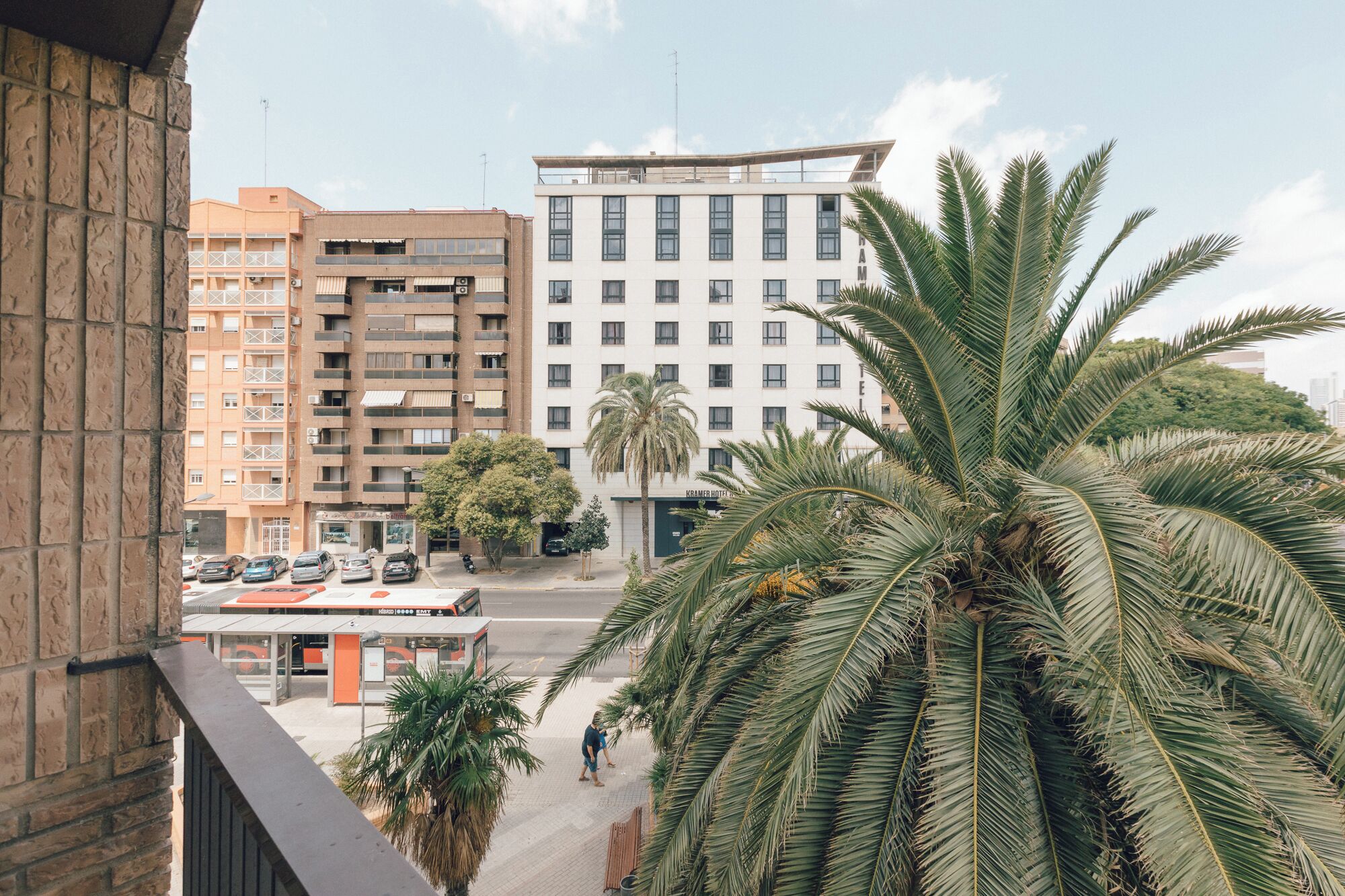 A multi-story hotel with a flat roof, a parking lot, and palm trees in the foreground.