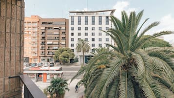 A multi-story hotel with a flat roof, a parking lot, and palm trees in the foreground.