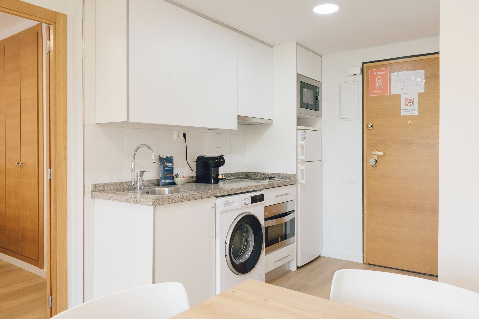 A compact kitchen with a washing machine, a microwave, and a coffee maker.