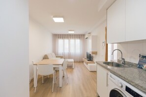 Uma cozinha moderna com máquina de lavar louça embutida, pia e área de refeições com mesa e cadeiras.
