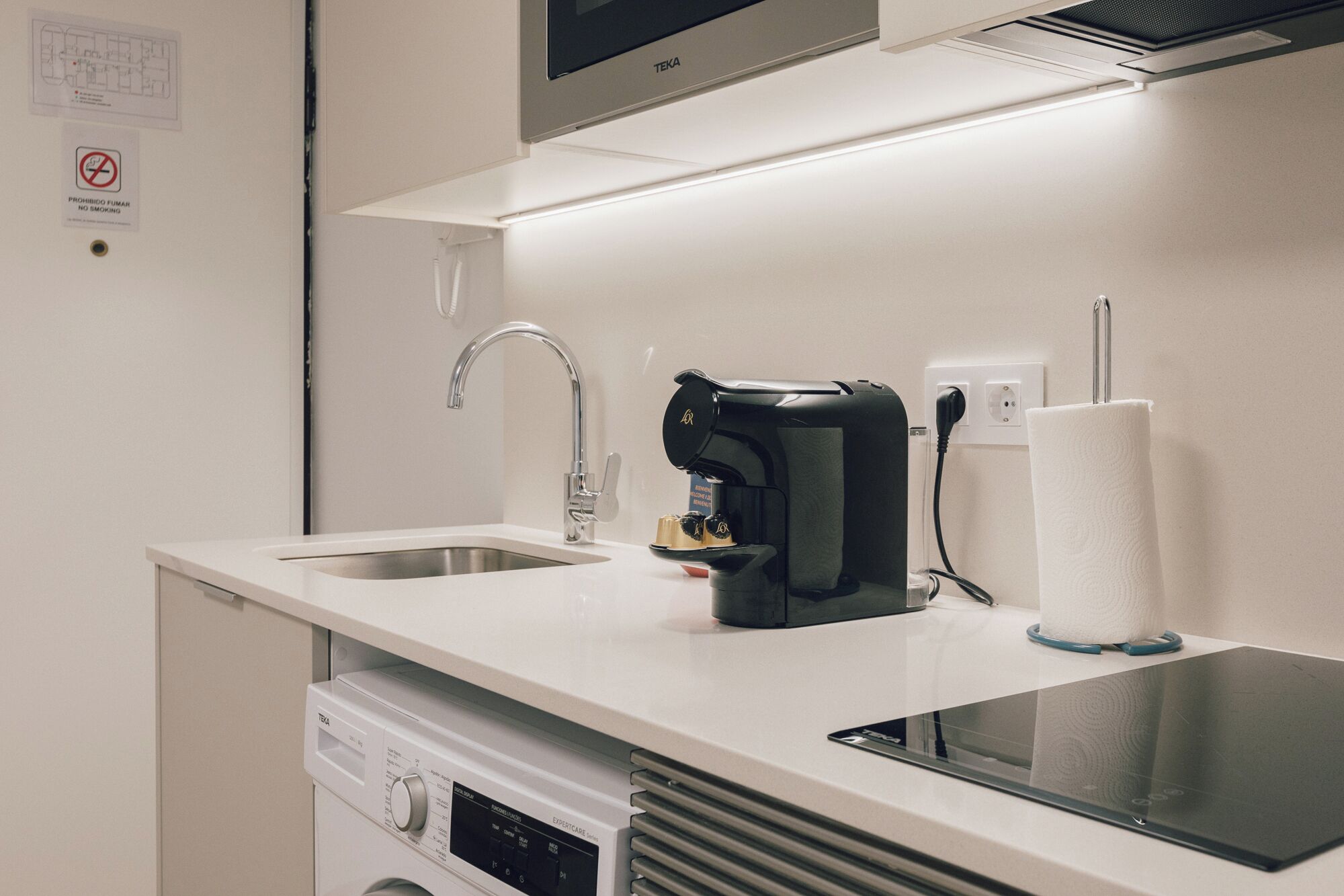A kitchenette with a coffee maker, a sink, and a paper towel dispenser.