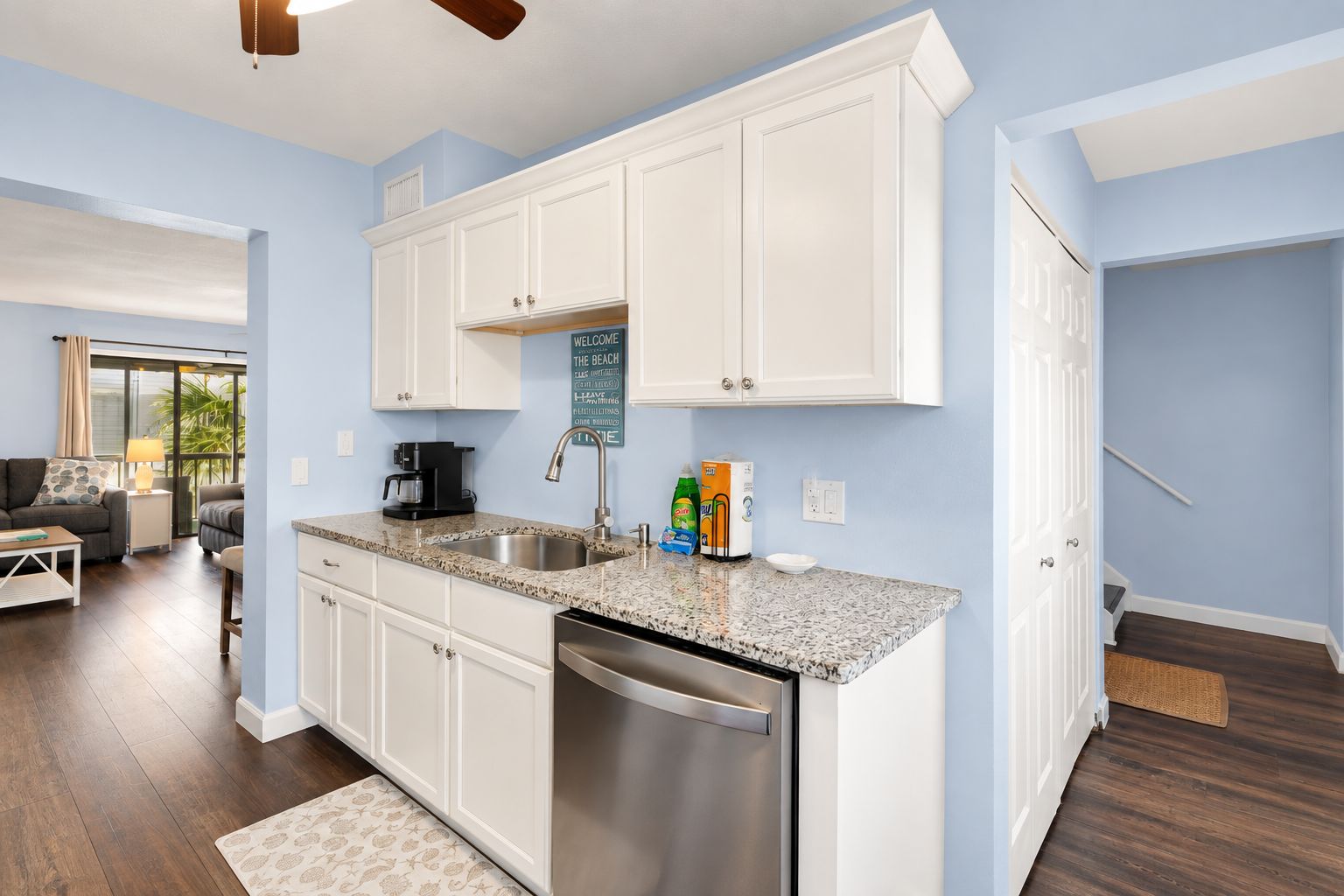 A modern kitchen with white cabinetry, a stainless steel dishwasher, and granite countertops.