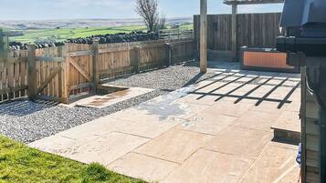 A patio with stone tiles, a wooden fence, and a pergola.