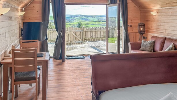A wooden interior with a bed, a desk, and a chair.