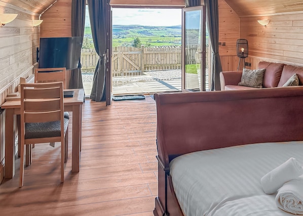 A wooden interior with a bed, a desk, and a chair.