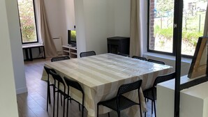 A dining area with a large table, chairs, a television, and a fireplace.