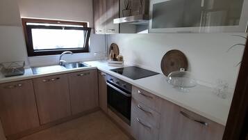 Comfort appartement, 1 slaapkamer, patio, uitzicht op tuin | Privékeuken | Een mini-koelkast, een oven, een kookplaat, een vaatwasser