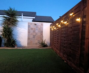 A backyard with artificial grass, a wooden fence, and a wall with patterned tiles. - La casita de Pepa, house with garden and a few minutes from the beach of El Palmar. (AN)