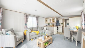 A modern living room with a sofa, coffee table, and dining area. - Platinum 3 Pets allowed Sleeps 6 (Fishguard, Pembrokeshire)