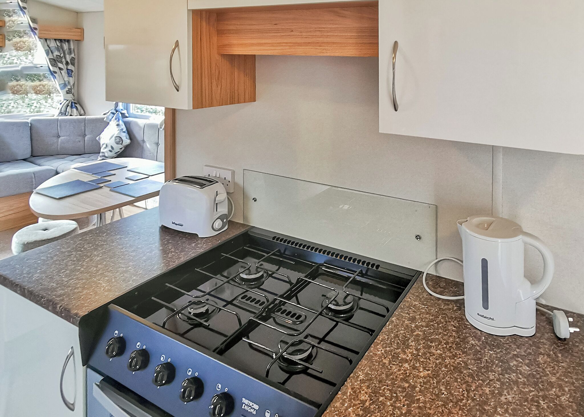 Une cuisine compacte équipée d’une cuisinière à gaz, d’une machine à café et d’un grille-pain.