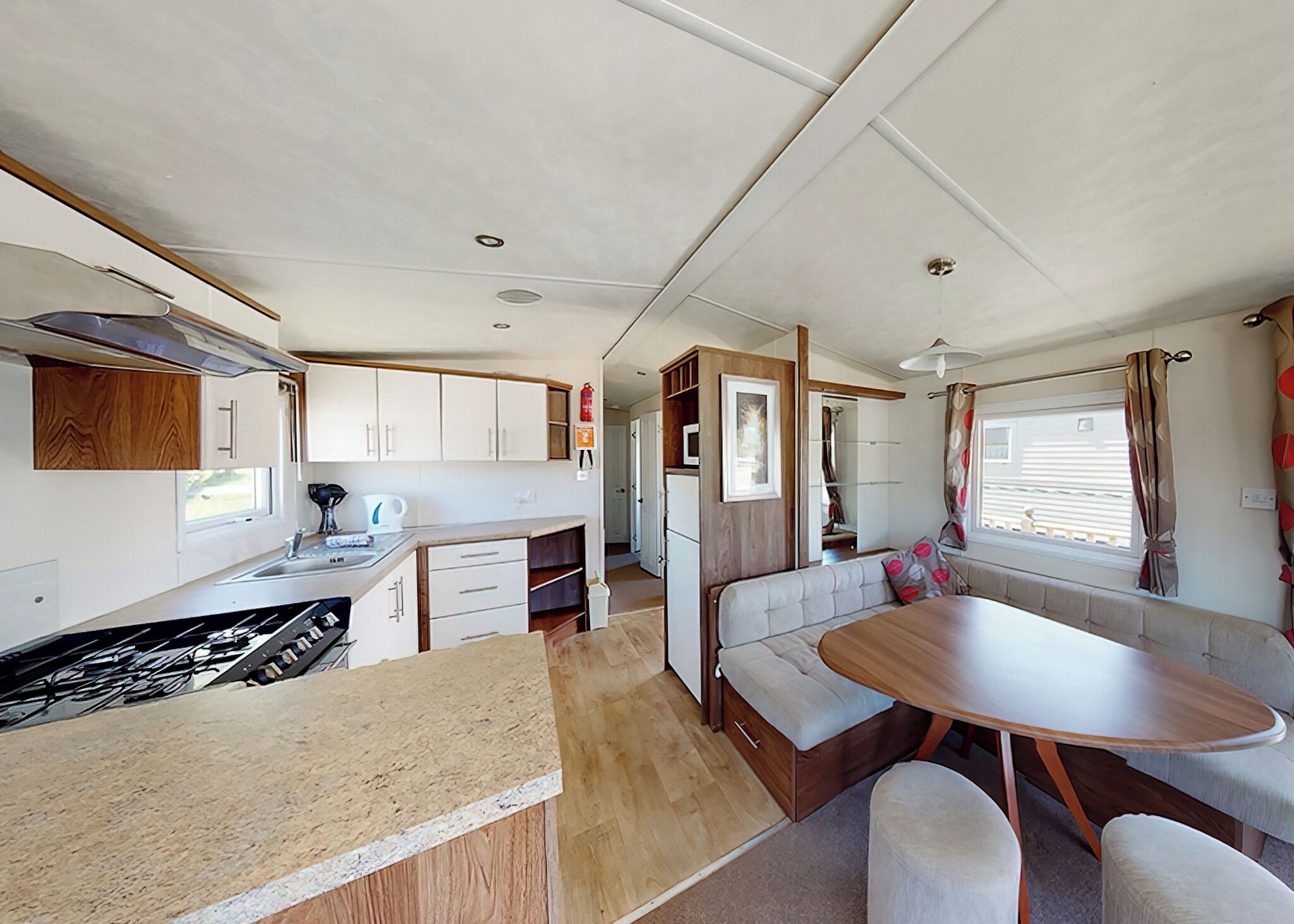 Interior compacto de una autocaravana con kitchenette, comedor y zona de estar.
