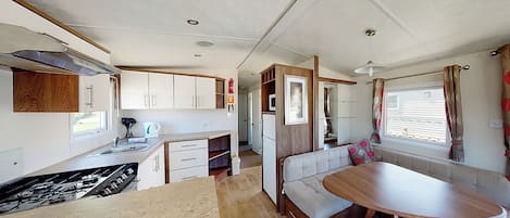 A compact RV interior with a kitchenette, a dining area, and a seating space.