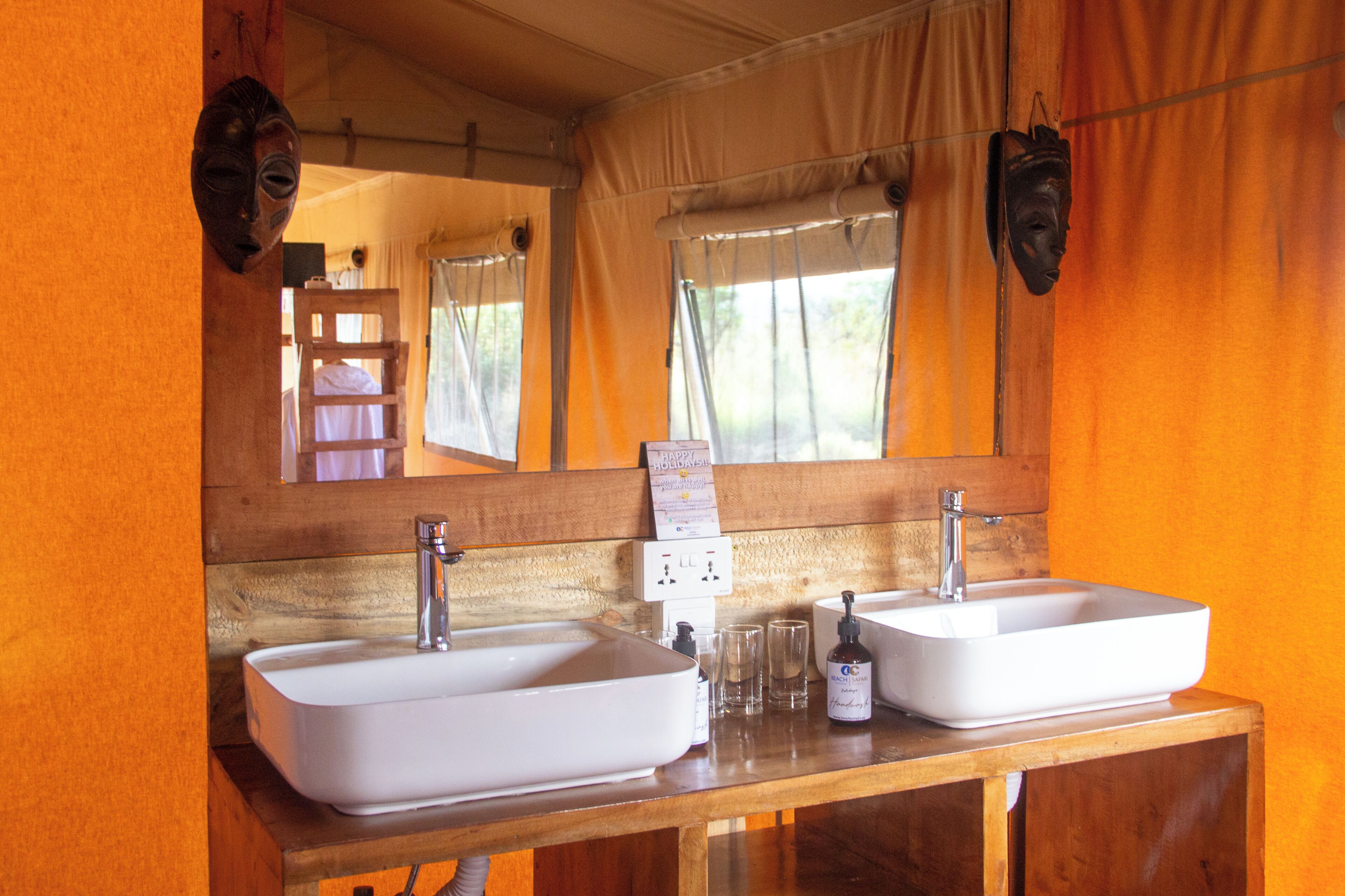 Un baño con dos lavamanos, un espejo y una ventana con cortinas.
