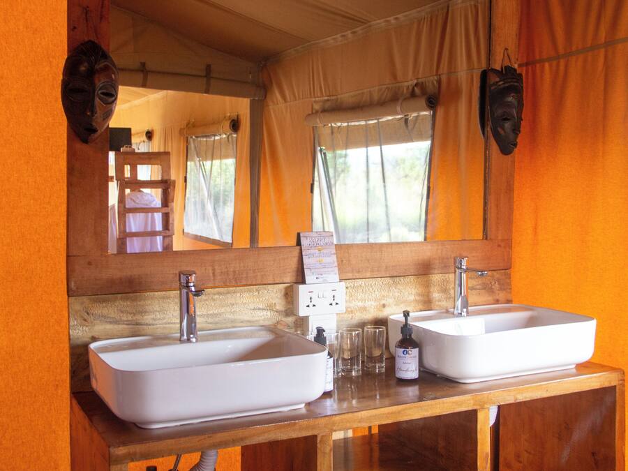 Un baño con dos lavamanos, un espejo y una ventana con cortinas.