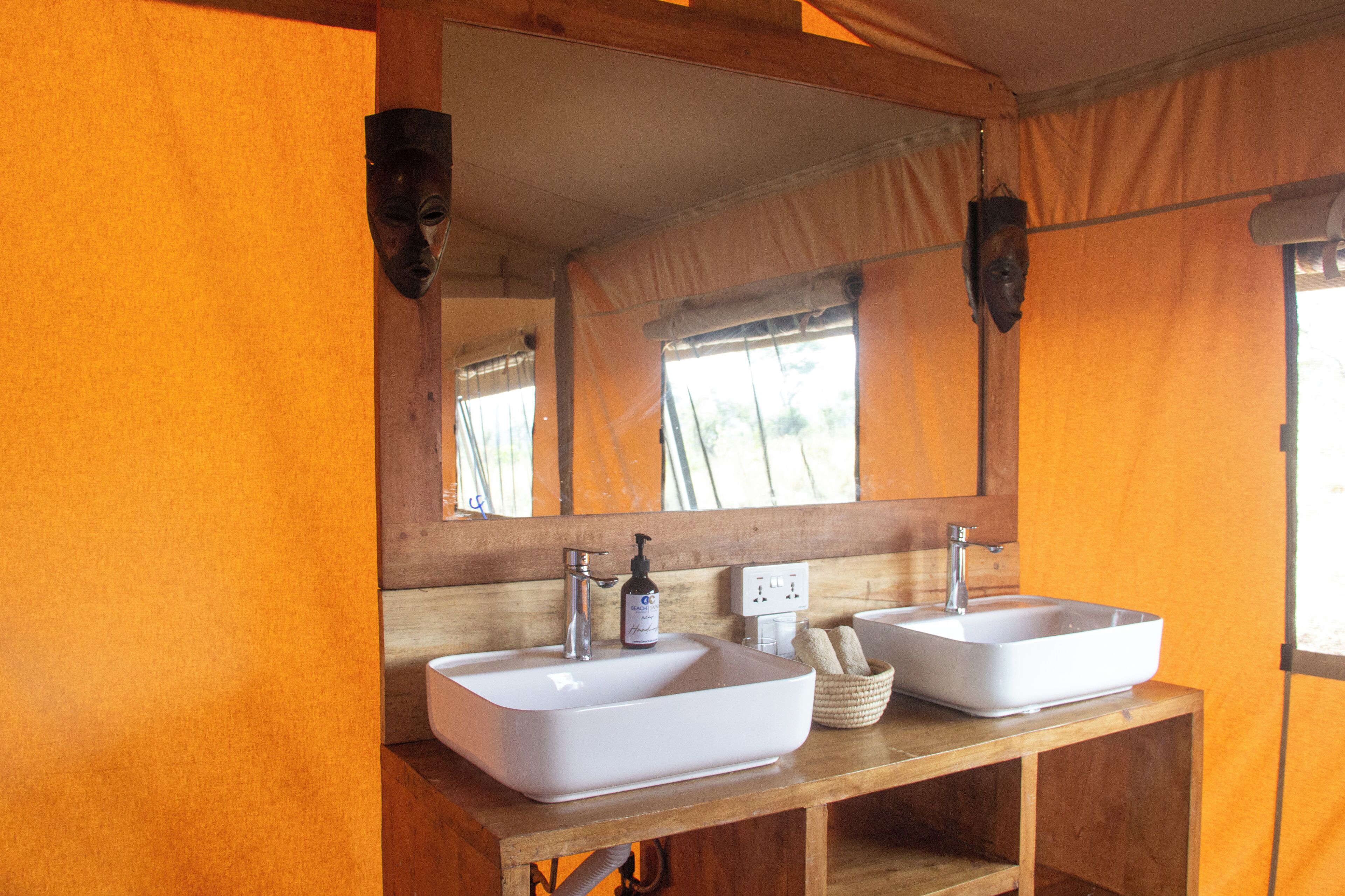 A bathroom with two sinks, a mirror, and a bottle of shampoo.