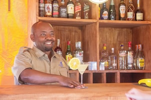A bartender at a bar with a variety of liquor bottles in the background.