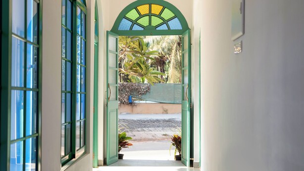 Un pasillo con un arco verde que conduce a un patio con plantas y vistas a la calle.