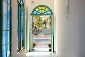 A hallway with a green archway leading to a courtyard with plants and a view of the street. - Casa Arvona (Calangute)