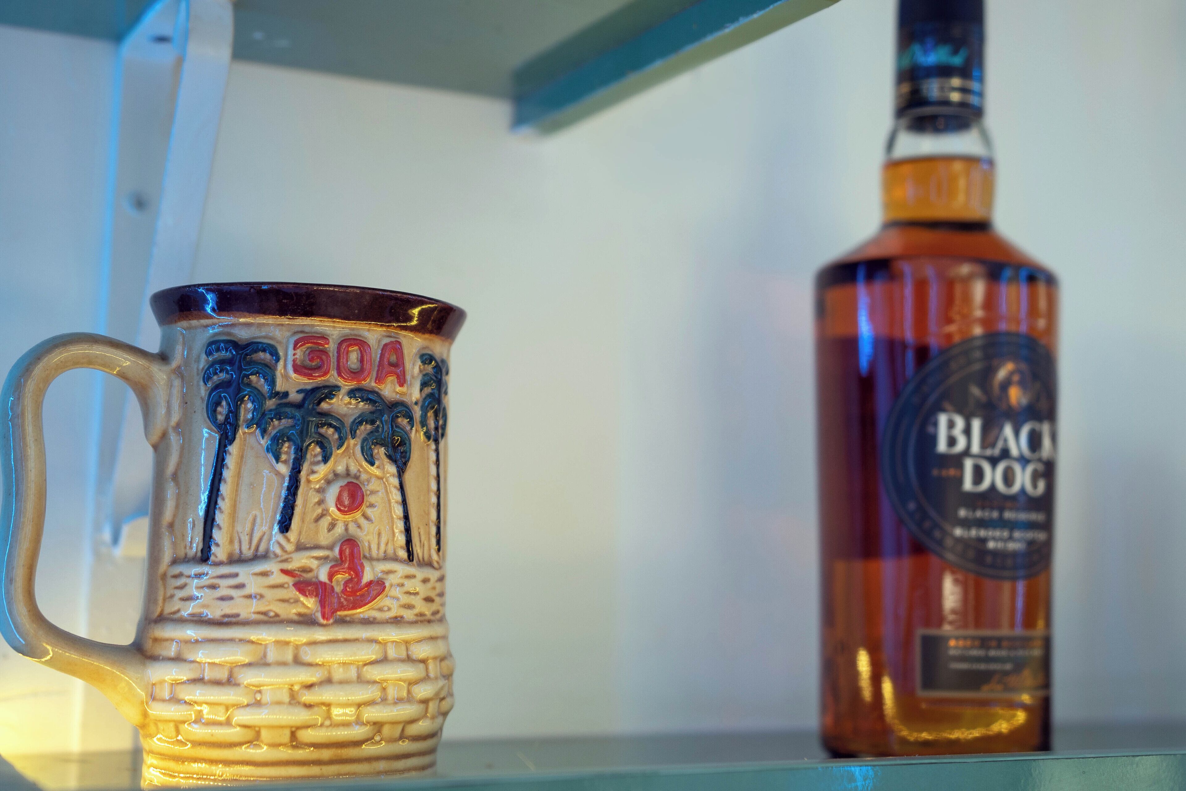 A ceramic mug with a beach scene and a bottle of Black Dog beer.