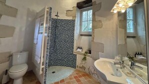A bathroom with a shower, toilet, sink, and a window.