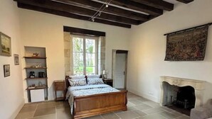 A bedroom with a wooden bed, a fireplace, a window, and a door.