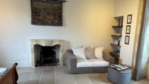 A living room with a fireplace, a sofa, a coffee table, and a wall with framed pictures.