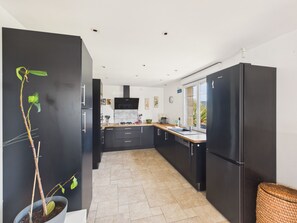 A modern kitchen with black cabinetry, a gas stove, and a large window. - House for 6 with jacuzzi and large garden (Treffiagat)
