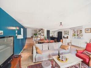 A living room with a sofa, a red armchair, a coffee table, and a television. - House for 6 with jacuzzi and large garden (Treffiagat)