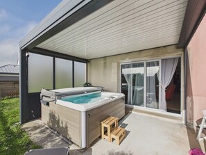 A hot tub in a covered outdoor area with a sliding glass door and a small wooden stool. - House for 6 with jacuzzi and large garden (Treffiagat)