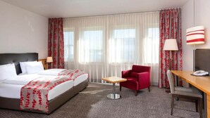 Ein Hotelzimmer mit einem Bett, einem Schreibtisch, einem Stuhl und einer Lampe.