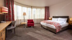 Una habitación de hotel con cama, escritorio, silla y lámpara.